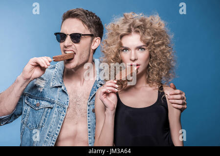 Ritratto di giovane ed elegante a mangiare il gelato isolato su blu Foto Stock