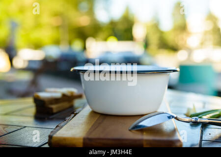 Close up metallo escursionismo ciotola con zuppa e cucchiaio di legno sul bordo esterno Foto Stock