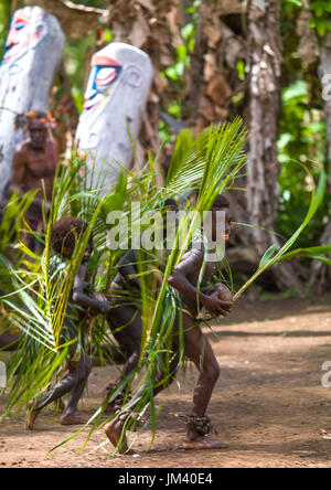 Piccoli bambini Nambas coperto con foglie di palmo ballando nella parte anteriore della fessura tamburi gong durante il palm tree danza, Malekula island, Gortiengser, Vanuatu Foto Stock