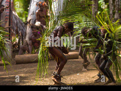 Piccoli bambini Nambas coperto con foglie di palmo ballando nella parte anteriore della fessura tamburi gong durante il palm tree danza, Malekula island, Gortiengser, Vanuatu Foto Stock