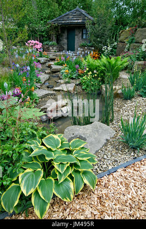 Un paese Garden cottage in una boscosa rockery con colorati piantagione Foto Stock