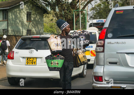 Un uomo che offre borse per la vendita ai conducenti bloccati nel traffico su autostrada Uhuru di Nairobi, in Kenya Foto Stock