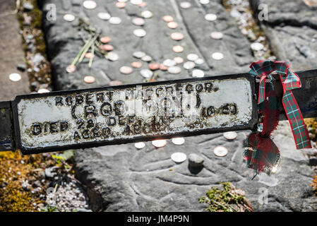 Le monete sulla tomba di Rob Roy MacGregor a Balquhidder kirkyard, Stirling, Scozia, Regno Unito