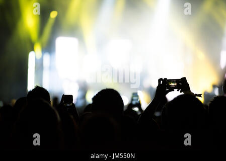 Silhouette di mani la registrazione di un concerto con i telefoni intelligenti. La folla di persone che utilizzano i telefoni intelligenti per fotografare un concerto Foto Stock