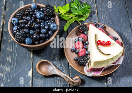 Una ciotola di frutti di bosco e una cheesecake. Bacche multicolori. Lay piatto. Il freddo dell'umore. Foto Stock