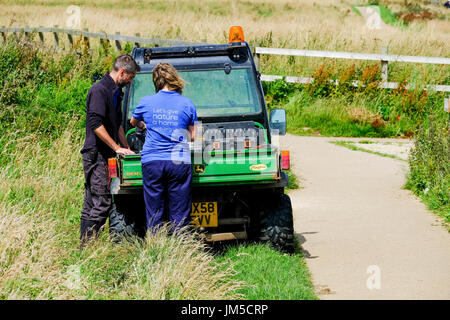 Due RSPB maschio e femmina di un uomo e di una donna personale Bempton Cliffs lavorare all'esterno da un buggy elettrico. Foto Stock