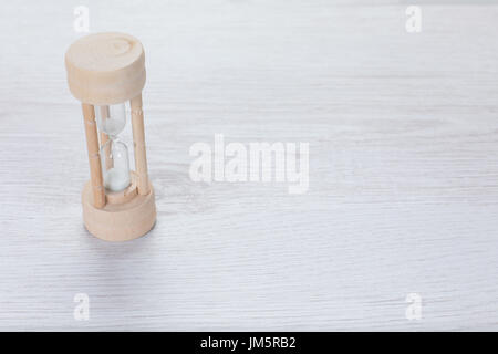 Semplice di legno clessidra misurando il tempo che passa un conteggio alla rovescia fino a un termine in business o come un timer in cottura su bianco goffrato legno con spazio di copia Foto Stock