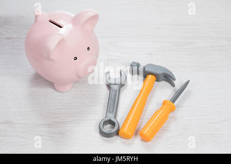 Strumenti di uso domestico con un salvadanaio concettuale dei costi o dei finanziamenti per le ristrutturazioni, DIY o la manutenzione e la riparazione visto da un angolo alto su w Foto Stock