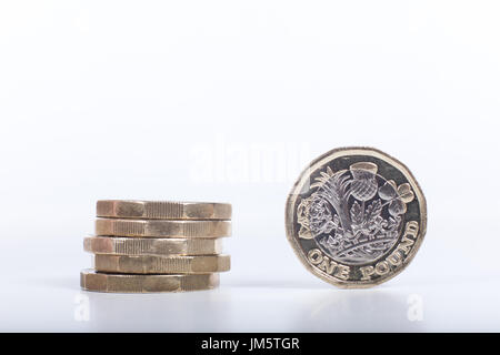 Pila di nuovo British una libbra di monete con uno in piedi sul suo lato che mostra la detial dell'incisione in una vista ravvicinata con spazio di copia Foto Stock