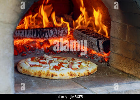 Flaming Hot pizza al forno a legna la cottura in un forno Foto Stock