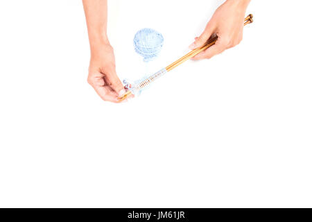 Donna con le mani in mano e aghi da maglia con il filo blu sfera su sfondo bianco Foto Stock
