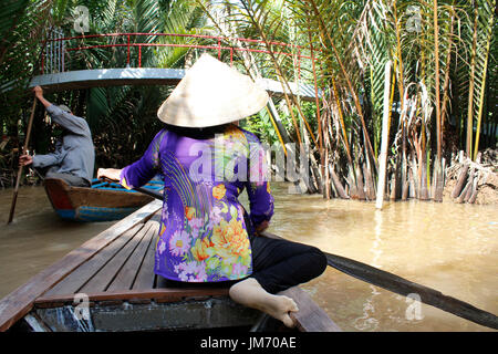 Donna vietnamita canottaggio un sampan (imbarcazione in legno) nel fiume Mekong, Ho Chi Minh Foto Stock