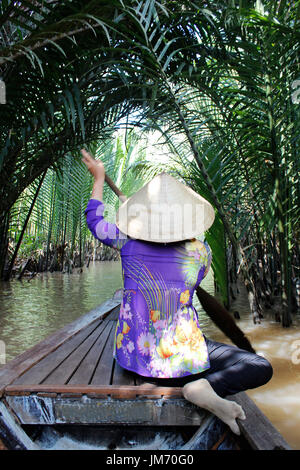 Donna vietnamita canottaggio un sampan (imbarcazione in legno) nel fiume Mekong, Ho Chi Minh Foto Stock