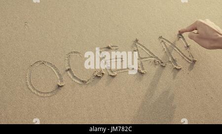 OCEAN scritto sulla spiaggia di sabbia lavata omaggio dalle onde. Foto Stock