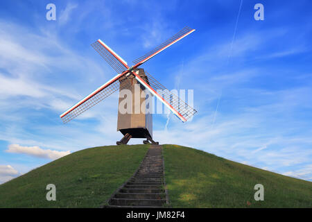 Mulino a vento sulla collina verde in una giornata di sole. Il mulino a vento di retrò sul cielo blu sullo sfondo. Punto di riferimento di Bruges. Foto Stock