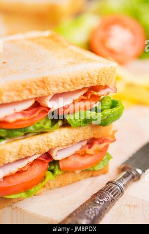 Un club sandwich su un tavolo rustico in condizioni di luce intensa. Foto Stock