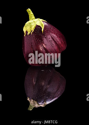 Uno viola melanzane con gocce di acqua isolate su nero con una vera riflessione Foto Stock