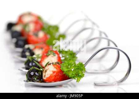 Caldi ripieni Peperoncini ciliegino, olive nere e formaggio feta su antipasto decorativo cucchiai Foto Stock