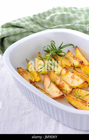 Patate al forno cunei con rosmarino in un piatto da forno Foto Stock