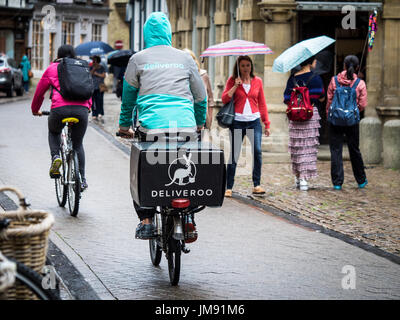 Deliveroo corriere - un cibo Deliveroo corriere consegna corse sotto la pioggia nel centro di Cambridge Regno Unito Foto Stock