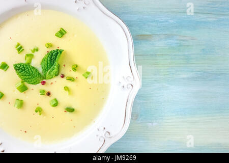 Un ingrandimento di foto aeree di vichyssoise, un francese di patate e porri minestra con cipollotti tritati, grani di pepe rosa e le foglie di menta per la decorazione Foto Stock