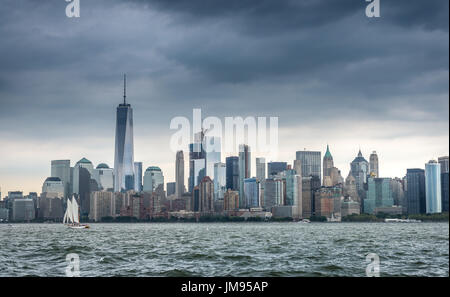 Fragoroso scure nuvole temporalesche sindone oltre la parte inferiore dello skyline di Manhattan e un piccolo yacht a vela sul fiume Hudson in New York New York, Stati Uniti d'America Foto Stock