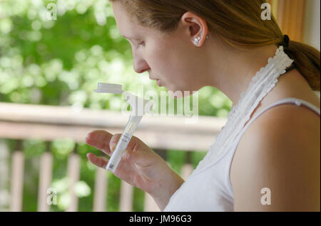 Ragazza la raccolta di saliva per un mail-in DNA gene kit di test per la filiazione e geni per la salute Foto Stock