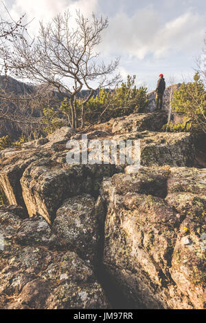 Escursionista in piedi sulle rocce e contempla un bellissimo paesaggio di montagna - wanderlust concetto di viaggio con gli sportivi a escursione nella natura selvaggia Foto Stock