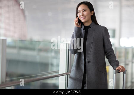 Imprenditrice cinese parlando al cellulare in aeroporto Foto Stock