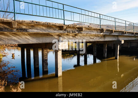 Vista del trascurato il vecchio ponte che consiste di lastre di cemento da qualche parte nel villaggio. Ponte sul fiume con acqua fangosa. Foto Stock