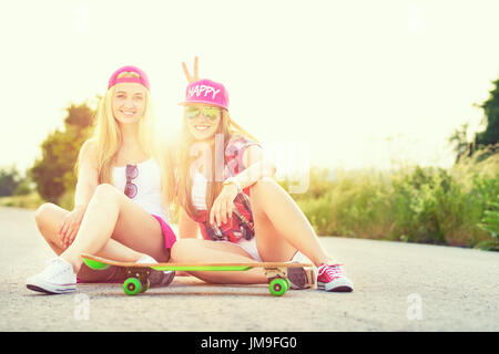 Attraente sorridente hipster teenage amici con lo skateboard, colorised immagine con la sunflare Foto Stock