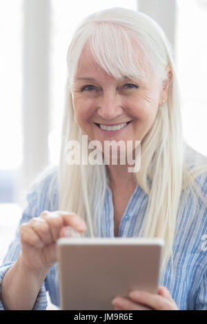 Ritratto di donna Senior con tavoletta digitale in casa Foto Stock
