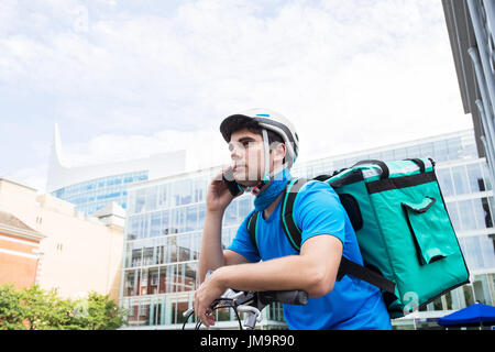 Servizi di corriere in bicicletta a consegnare il cibo in città utilizzando il telefono cellulare Foto Stock