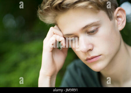 Close up infelice ragazzo adolescente seduti all'aperto Foto Stock