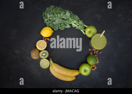 Uno stile di vita sano concetto con un bicchiere di verde circondato frullato di frutta e verdura in una forma circolare con una stanza per il testo. Foto Stock