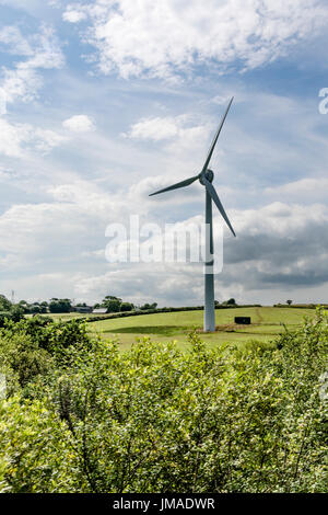 Turbina eolica gigante / generatore di vento in campo contro cielo blu e sole. Metafora energia pulita, energie rinnovabili, energia eolica. Paesaggio con turbina eolica Foto Stock