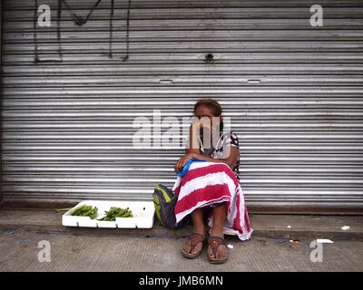 ANTIPOLO City, Filippine - Luglio 19, 2017: una donna vende verdure a un marciapiede lungo una strada di Antipolo City. Foto Stock
