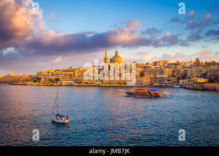La Valletta, Malta - Imbarcazioni a vela in corrispondenza delle pareti della Valletta con Saint Paul Cathedral e bellissimo Cielo e nubi al mattino Foto Stock