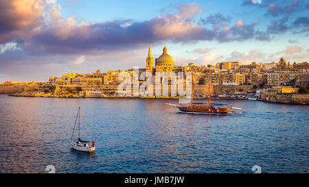 La Valletta, Malta - Imbarcazioni a vela in corrispondenza delle pareti della Valletta con Saint Paul Cathedral e bellissimo Cielo e nubi al mattino Foto Stock