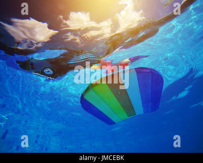 Rainbow styrofoam modello scheda di nuoto o zoccolo galleggianti in piscina di acqua, estate vacanze attività ricreative oggetto nel poolsid Foto Stock