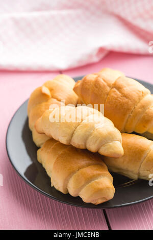 Dolce gustoso croissant sulla tabella di rosa. Foto Stock