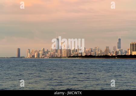 Un muto sunrise getta luce le nuvole al di sopra di una porzione sullo skyline di Chicago e del lago Michigan. Chicago, Illinois, Stati Uniti d'America. Foto Stock