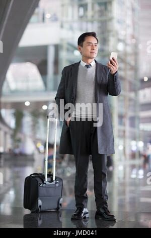 Imprenditore cinese utilizzando smart phone in aeroporto Foto Stock