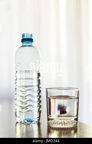 Bicchiere di acqua e una bottiglia di plastica Foto Stock