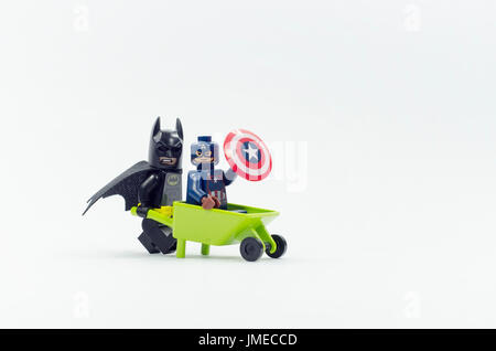 Lego Captain America minifigure seduti sulla carriola mentre batman spingendolo, isolato su sfondo bianco. Foto Stock