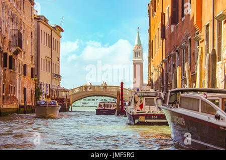Colori smorzati e soft focus immagine di una bella giornata a Venezia con la torre campanaria e il bridge con coppia su di essa e la polizia di barche in laguna Foto Stock