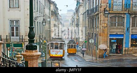 Lisbona, Portogallo - 2 Maggio 2012: la nebbia e la pioggia in città, il giallo tram ride lungo la strada Conceicao lungo gli edifici ad umido, il 2 maggio Foto Stock