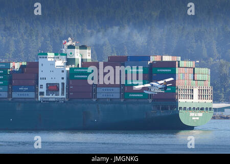 Il floatplane Harbour Air Turbo Otter si trova oltre la nave gigantesco Evergreen Container Ship "Ever Ulysses" nel porto di Vancouver, British Columbia, Canada. Foto Stock