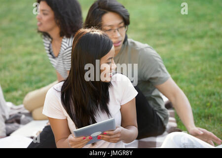Foto del gruppo multietnico di giovani sorridendo gli studenti che studiano all'esterno. Guardando a parte. Foto Stock