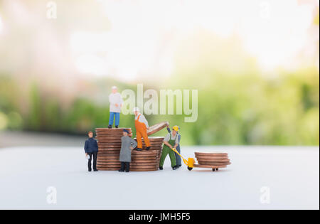 Imprenditore in miniatura e lavoratore in piedi sulle monete e il trasporto di monete utilizzando come un concetto di business. Foto Stock